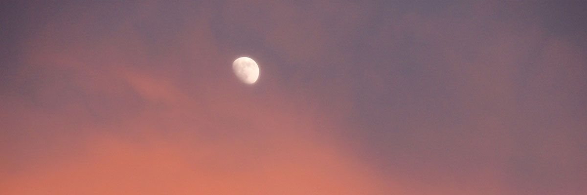 The moon through sun-blushed clouds